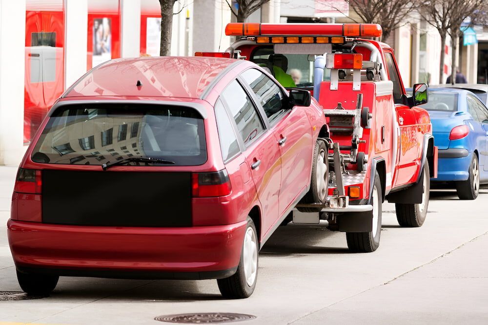 Red Car Being Towed by a Red Tow Truck on a City Street — Fulgi's South Coast Automotive and Dismantling in Nowra, NSW