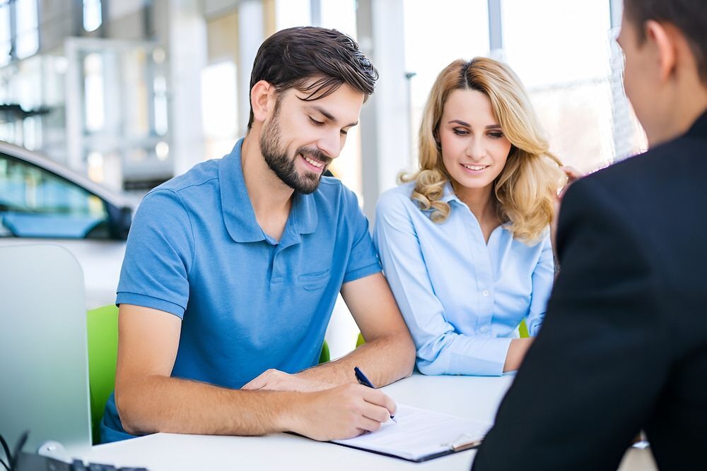 Couple Signing Paperwork With a Salesperson in a Car — Fulgi's South Coast Automotive and Dismantling in Ulladulla, NSW