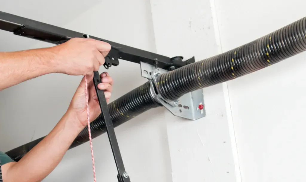 Hands adjusting a garage door spring.