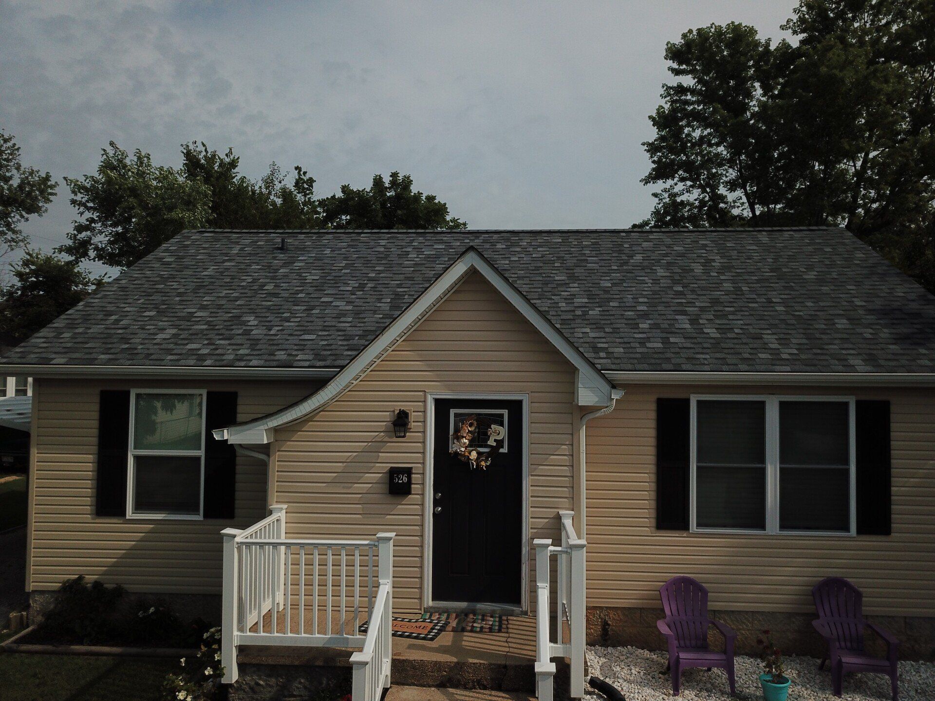 A small house with a black door and purple chairs in front of it