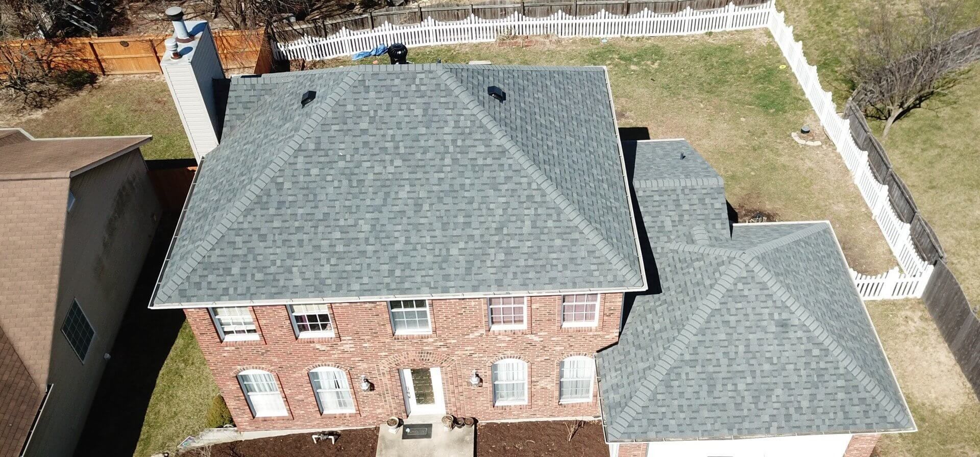 An aerial view of a large brick house with a gray roof.