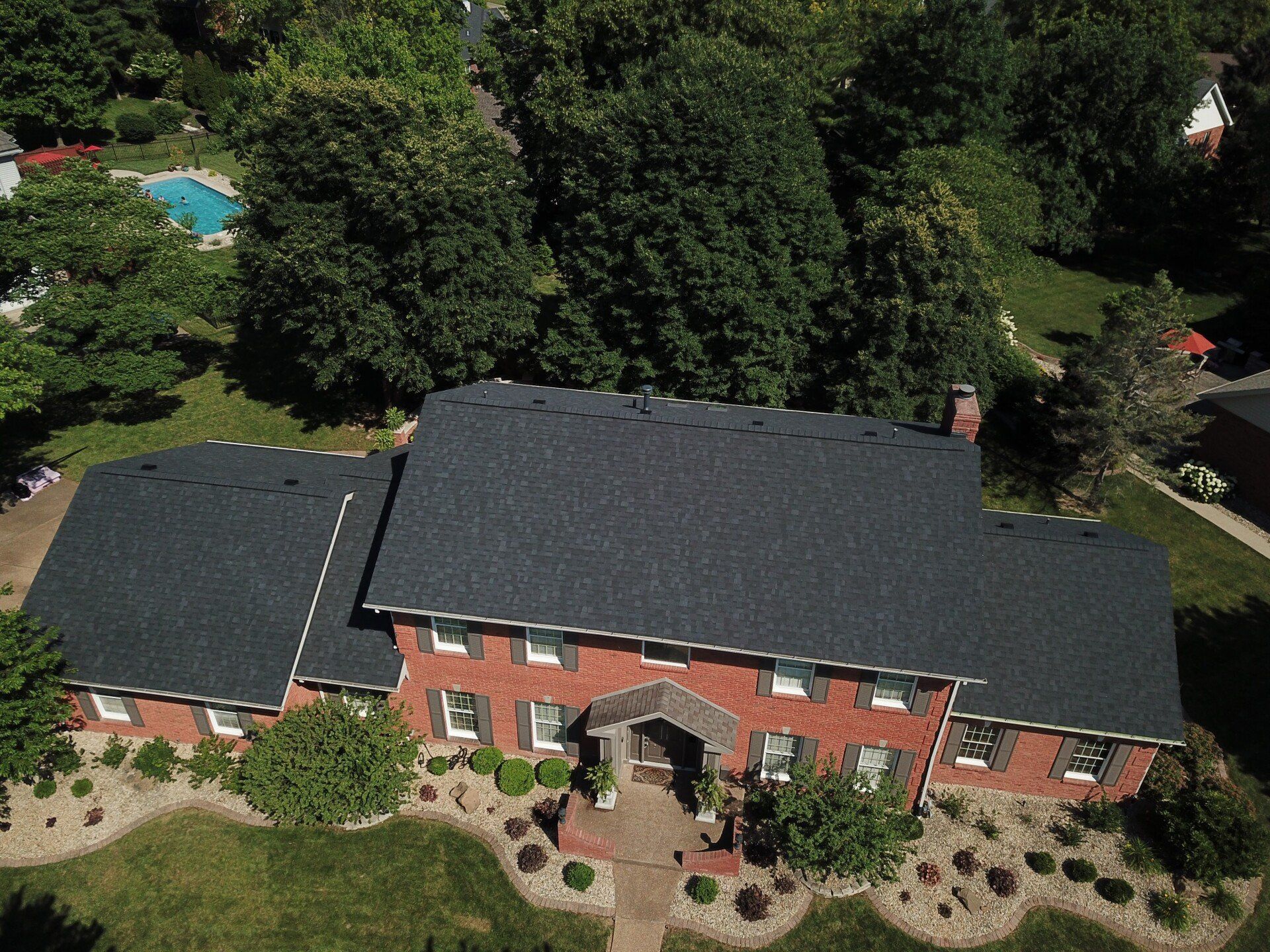 An aerial view of a large brick house with a black roof