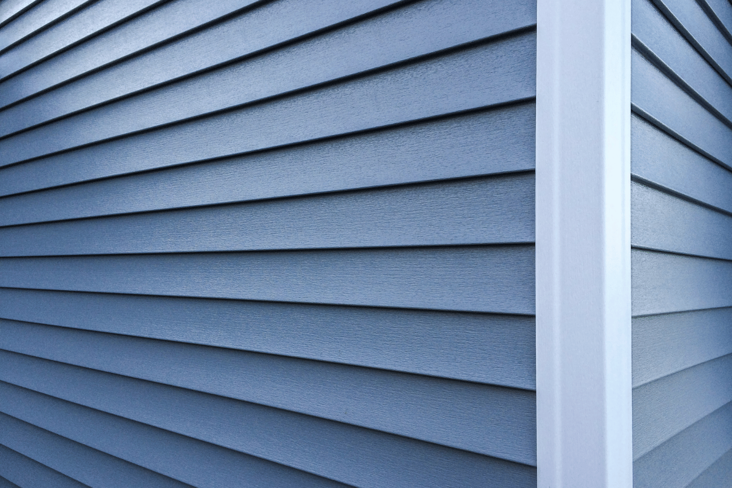 A close up of a blue siding on a house with a white trim.