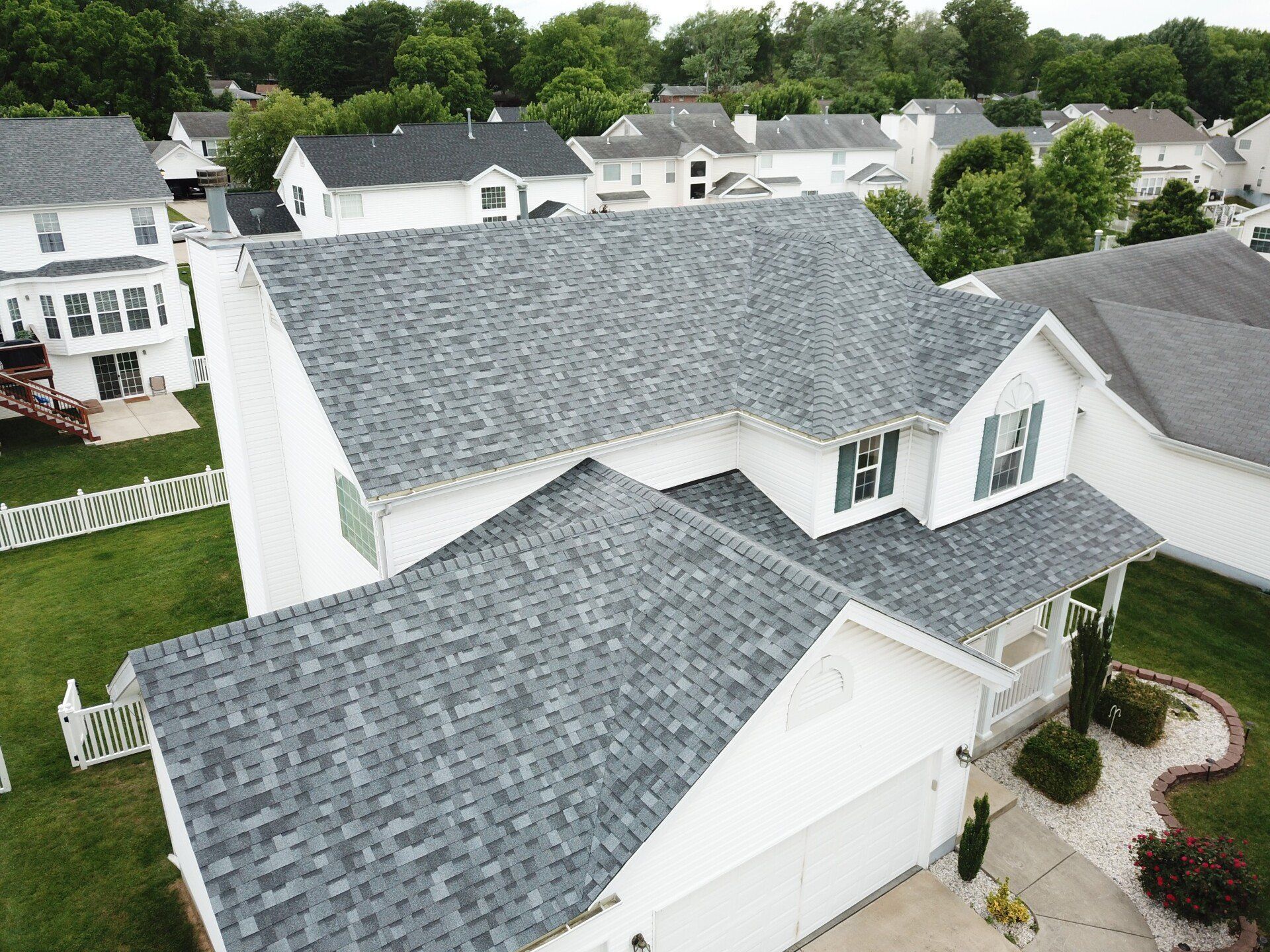 An aerial view of a white house with a gray roof