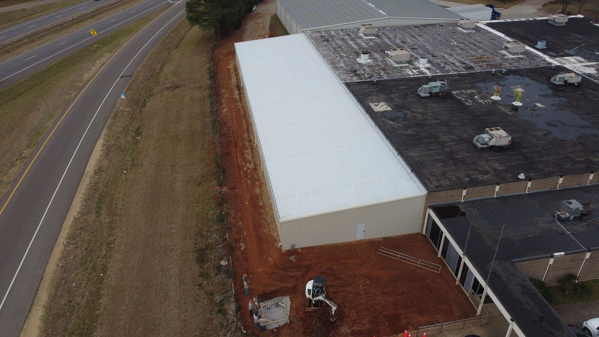 An aerial view of a building under construction next to a highway.
