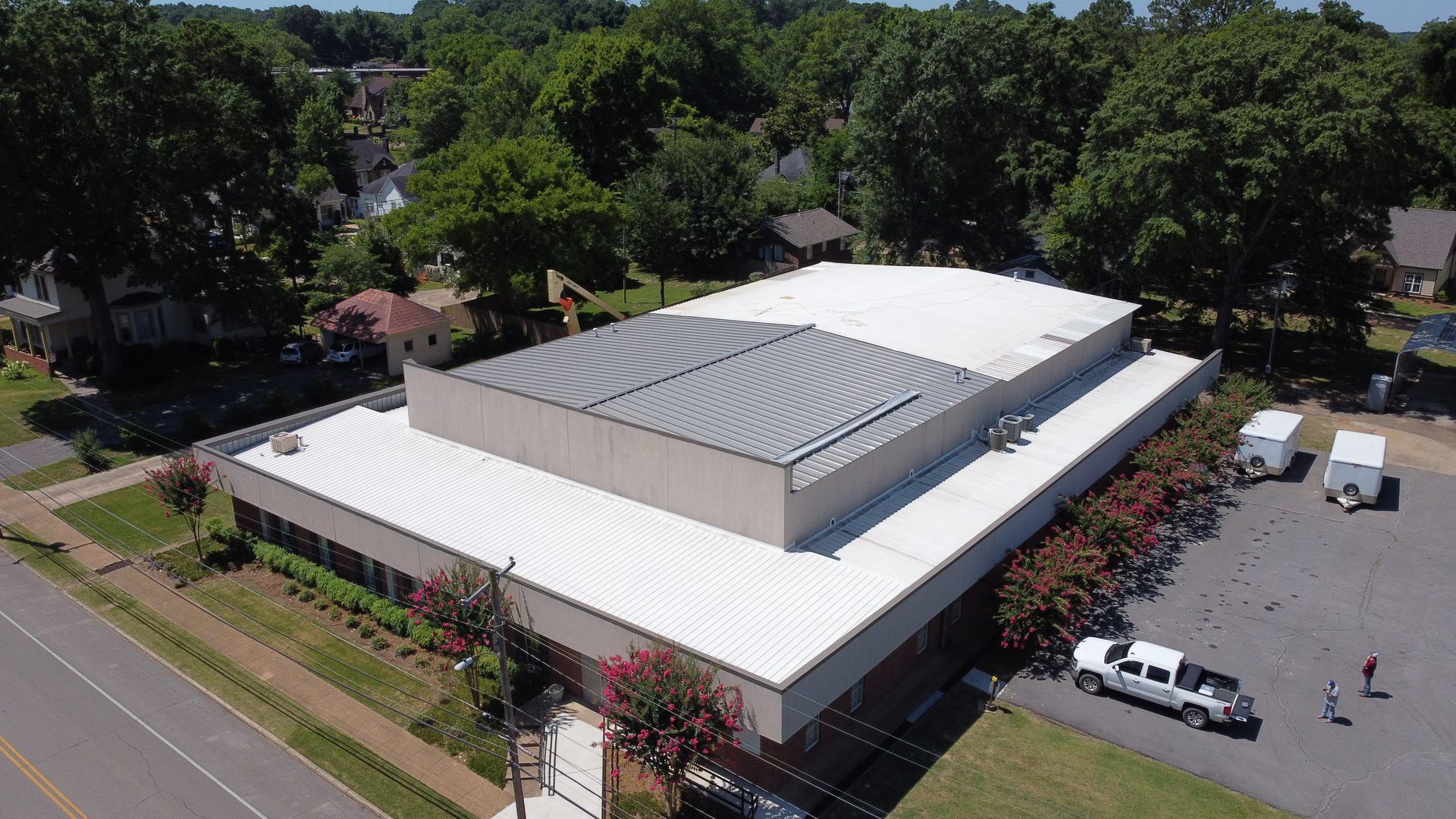 An aerial view of a large building with a white roof surrounded by trees.