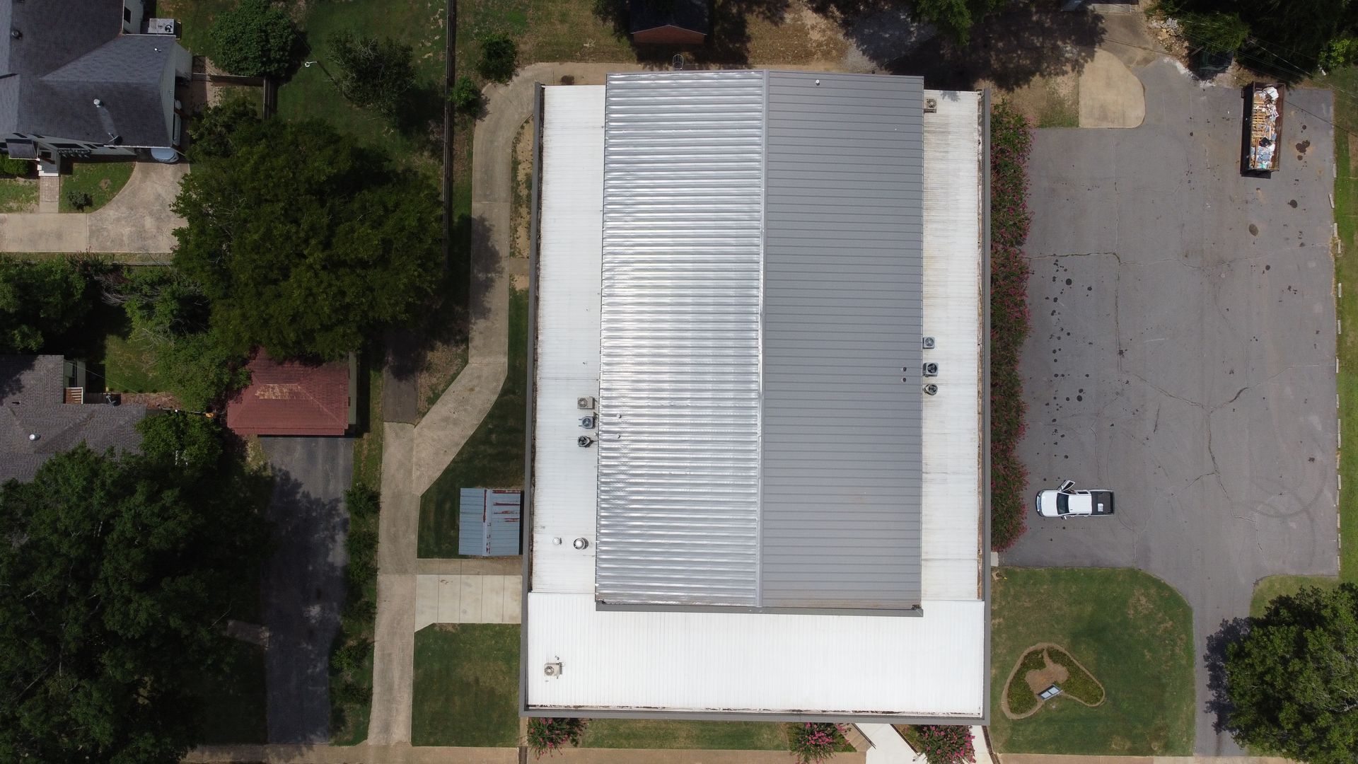 An aerial view of a large building with a white roof in a residential area.