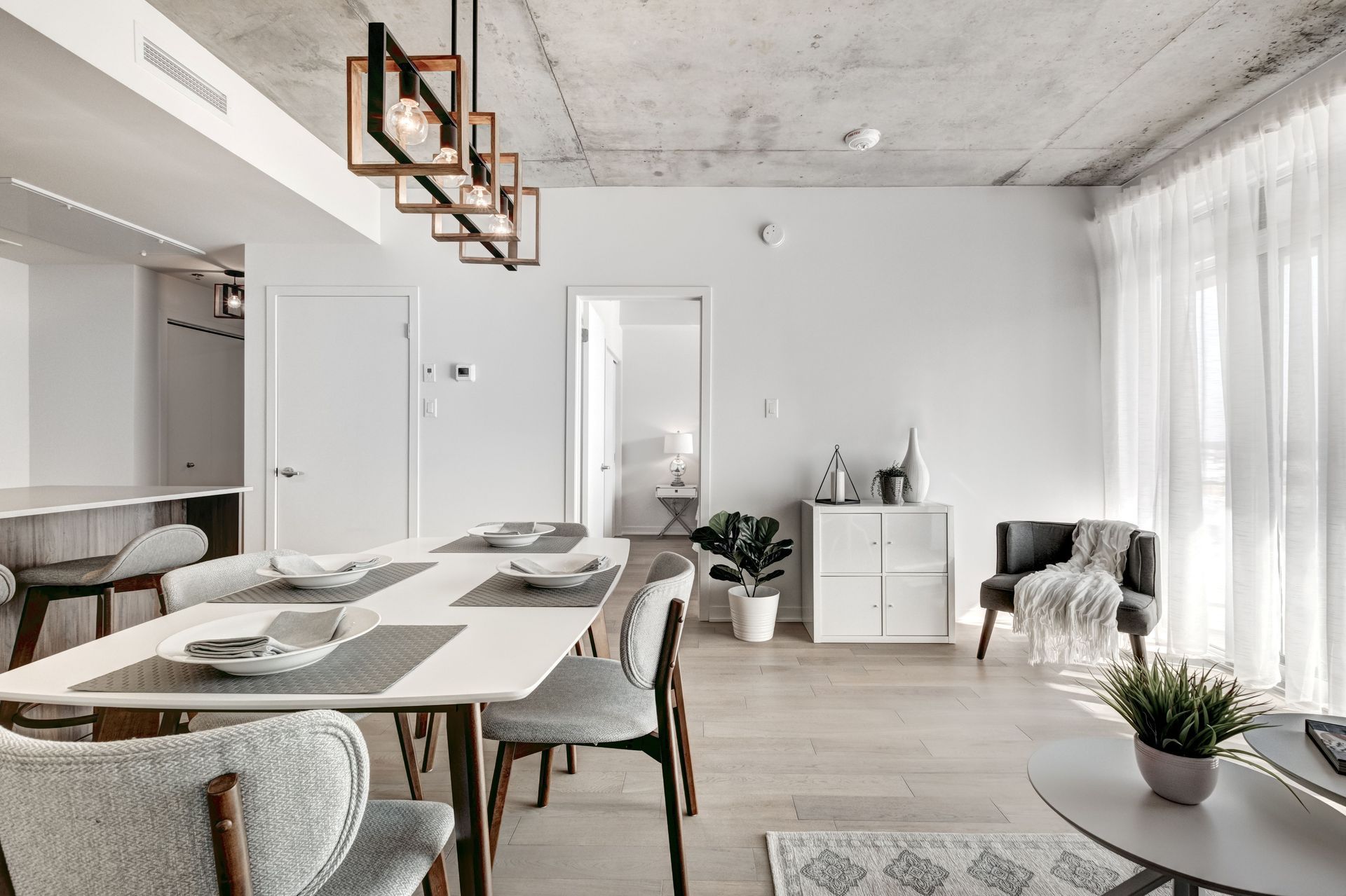 A luxurious kitchen area of a home, with white walls, table and chairs.