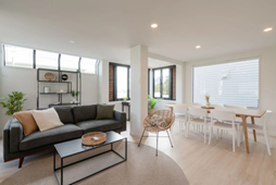 A minimalistic living room area inside a home, with windows letting in natural light.