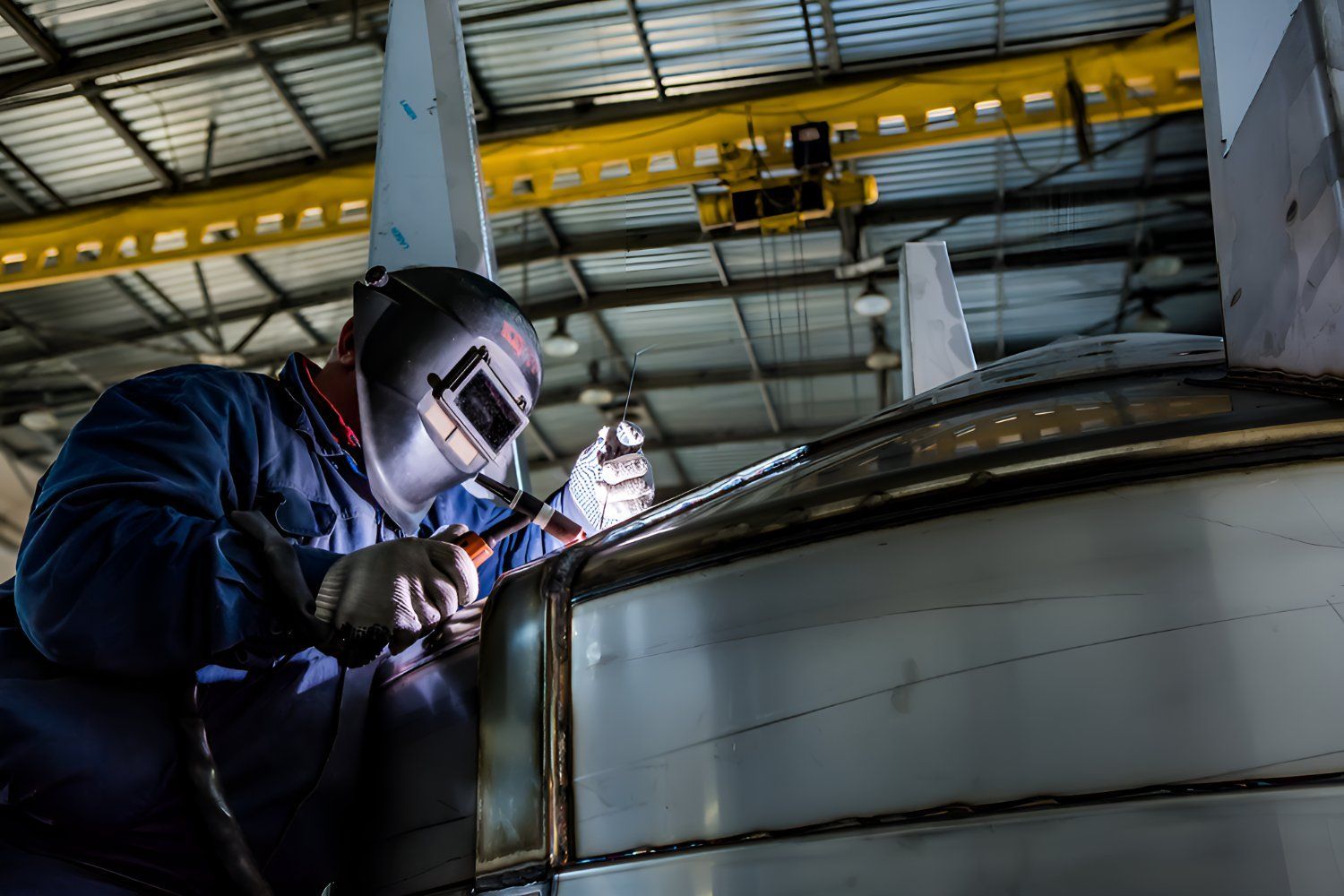 A Man Is Welding A Piece Of Metal In A Factory — Sno's Welding In Ciccone, NT