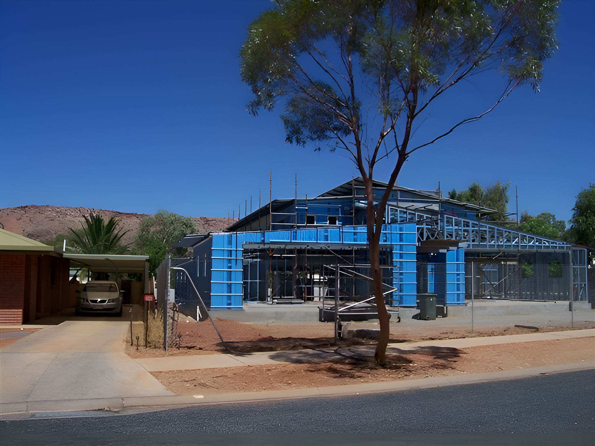 A House Under Construction With Blue Scaffolding Around It — Sno's Welding In Ciccone, NT