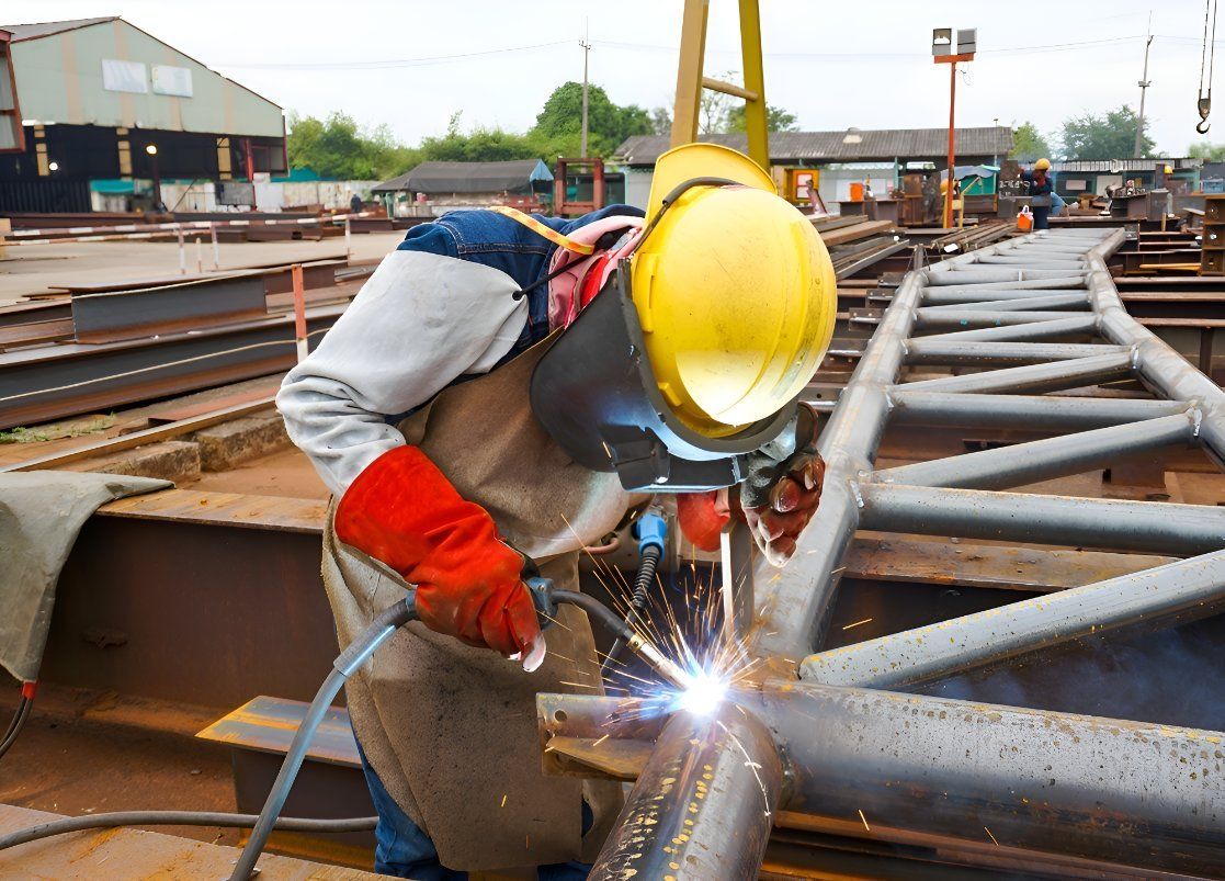 A Man Is Welding A Metal Pipe In A Factory — Sno's Welding In Ciccone, NT