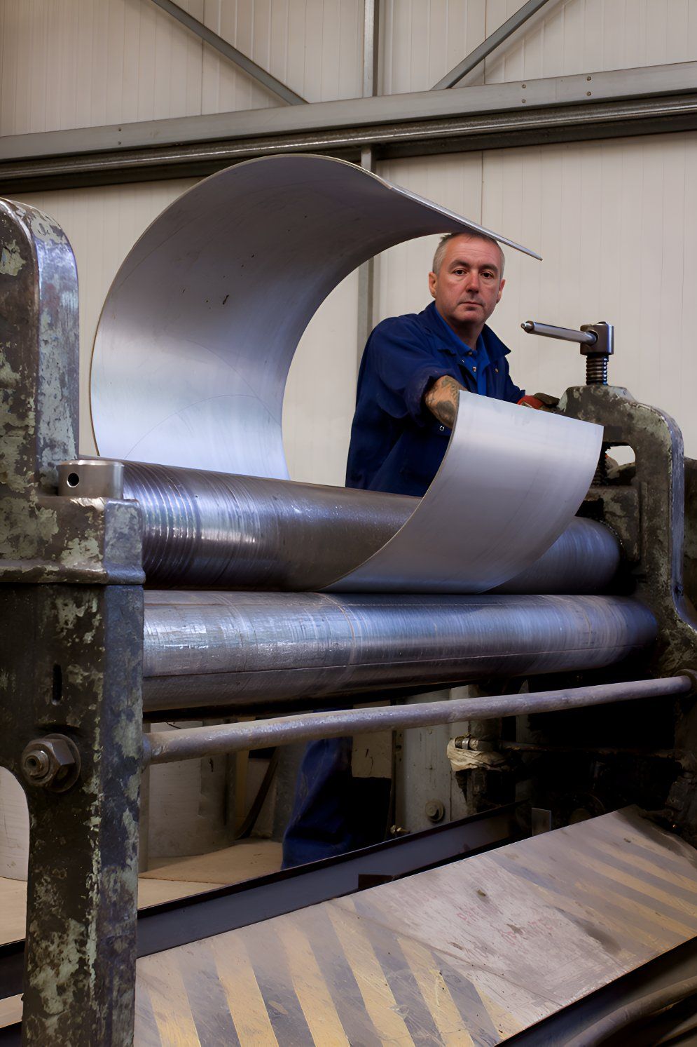 A Man Is Using A Machine To Roll A Piece Of Metal — Sno's Welding In Ciccone, NT