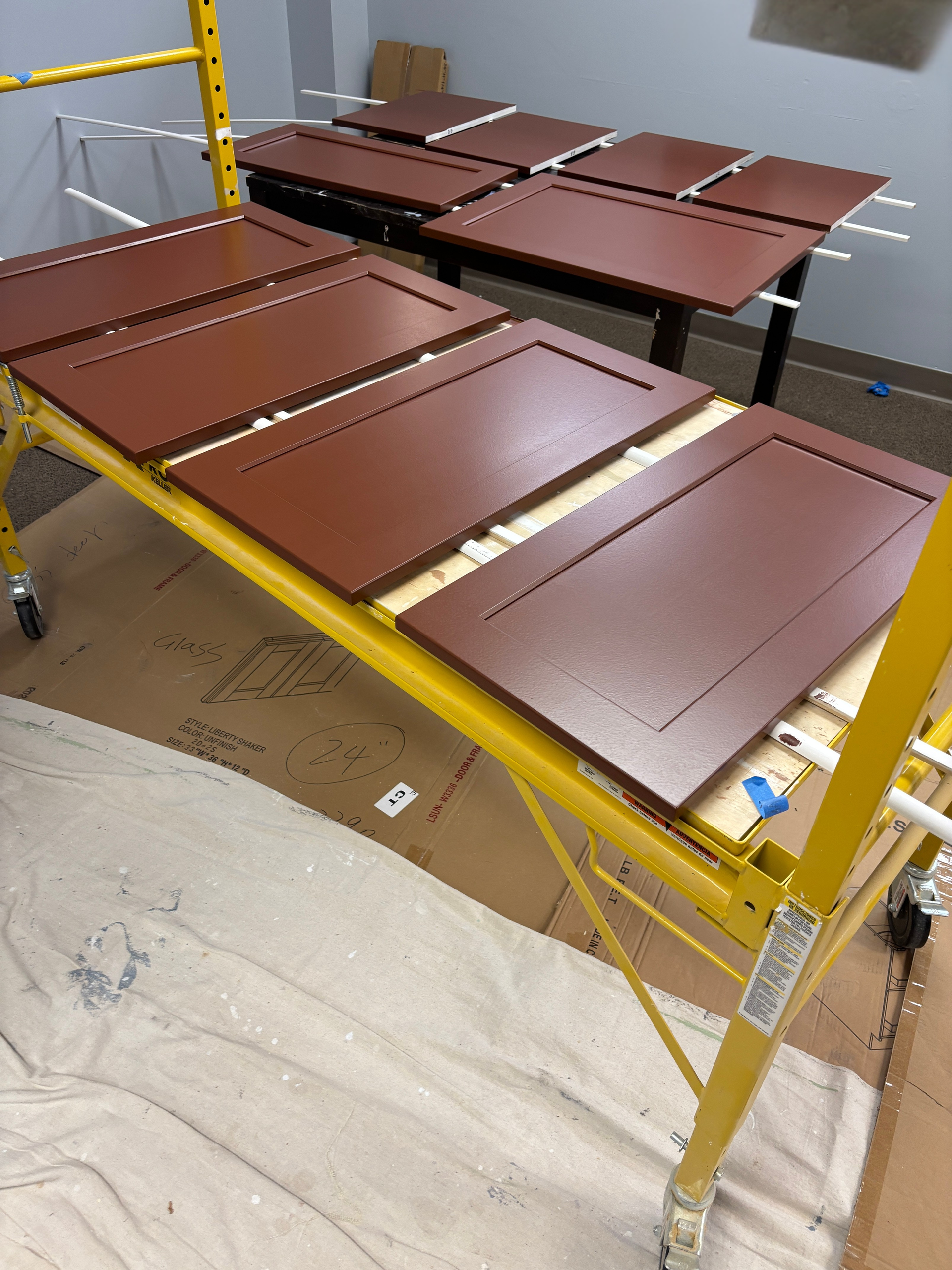 Brown panels stacked on a yellow metal rack in a workshop or storage area