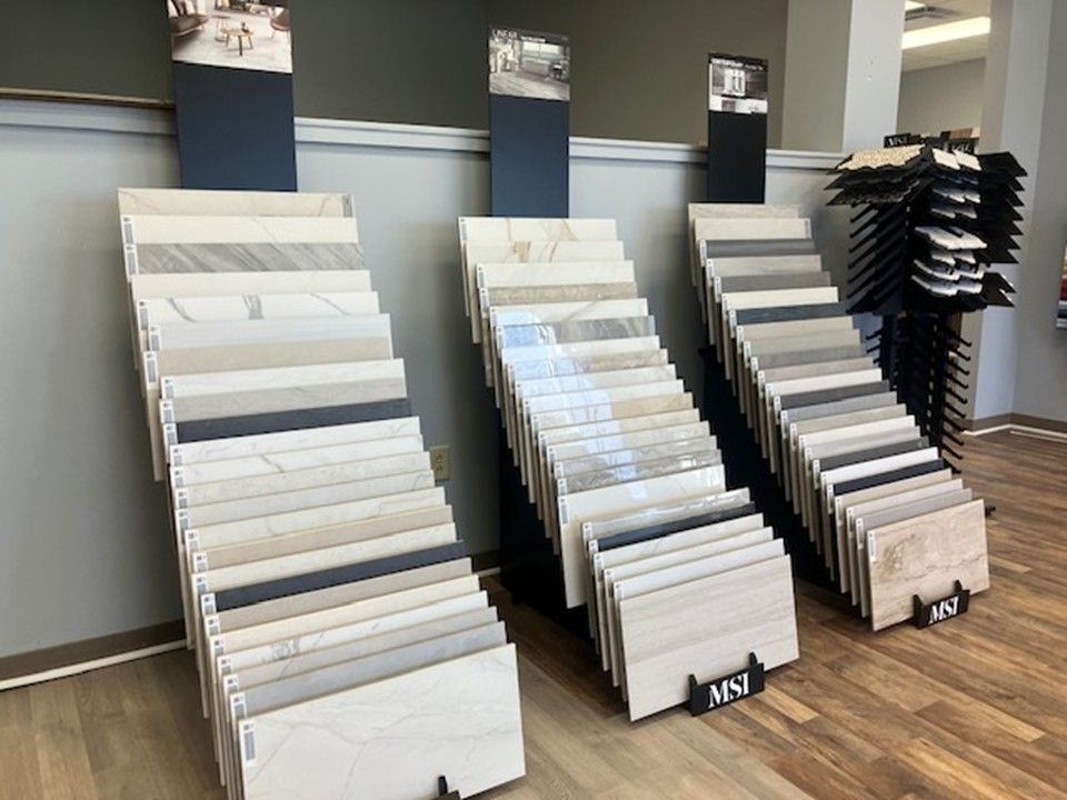 Flooring showroom with display racks of sample planks and tiles on a wood floor