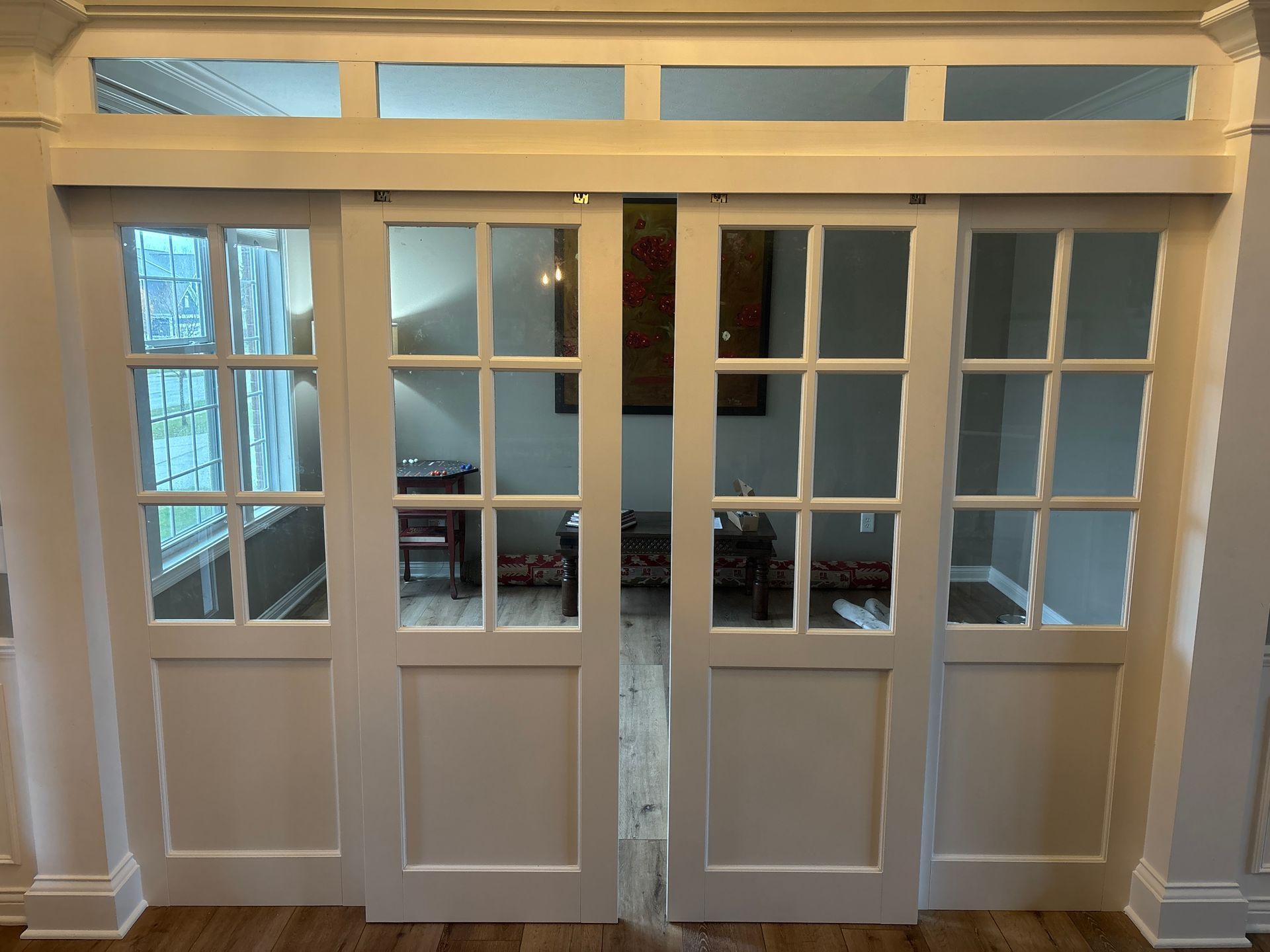 White French doors with glass panels and transom windows in a bright interior hallway