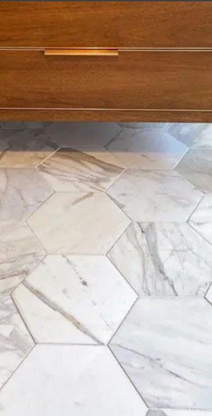 Wooden cabinet with brass handle above a white marble tile floor.