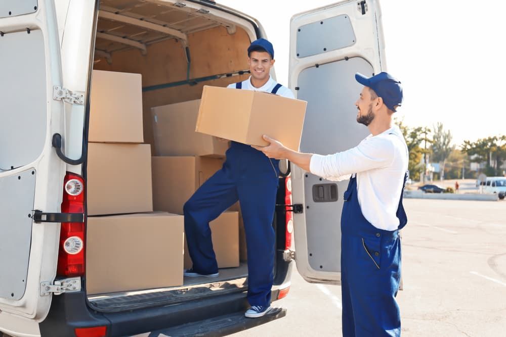 Two Delivery Men Are Loading Boxes Into A Van — South Burnett Truck Rental In Maryborough, QLD