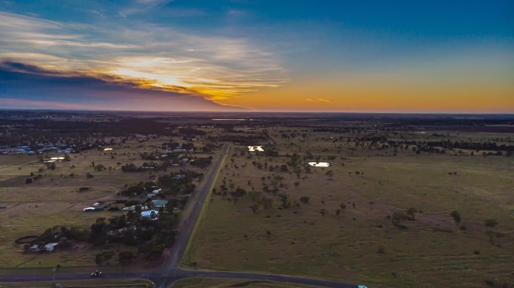 An Aerial View Of A Road Going Through A Field At Sunset — South Burnett Truck Rental In Roma, QLD
