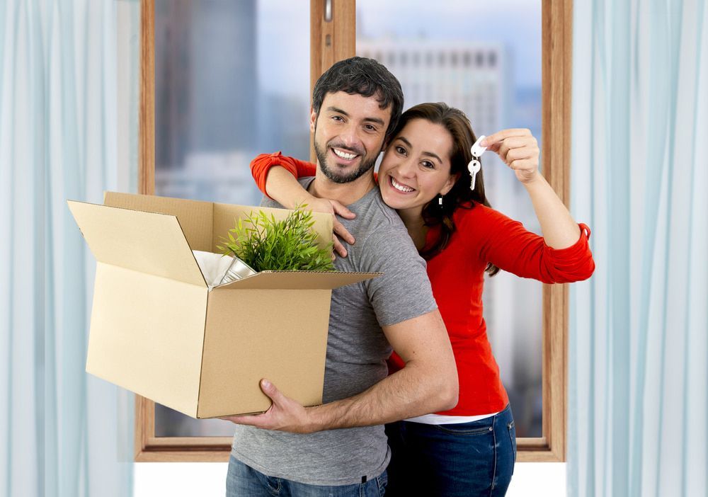 A Man And A Woman Are Holding A Cardboard Box And Keys — South Burnett Truck Rental In Childers, QLD