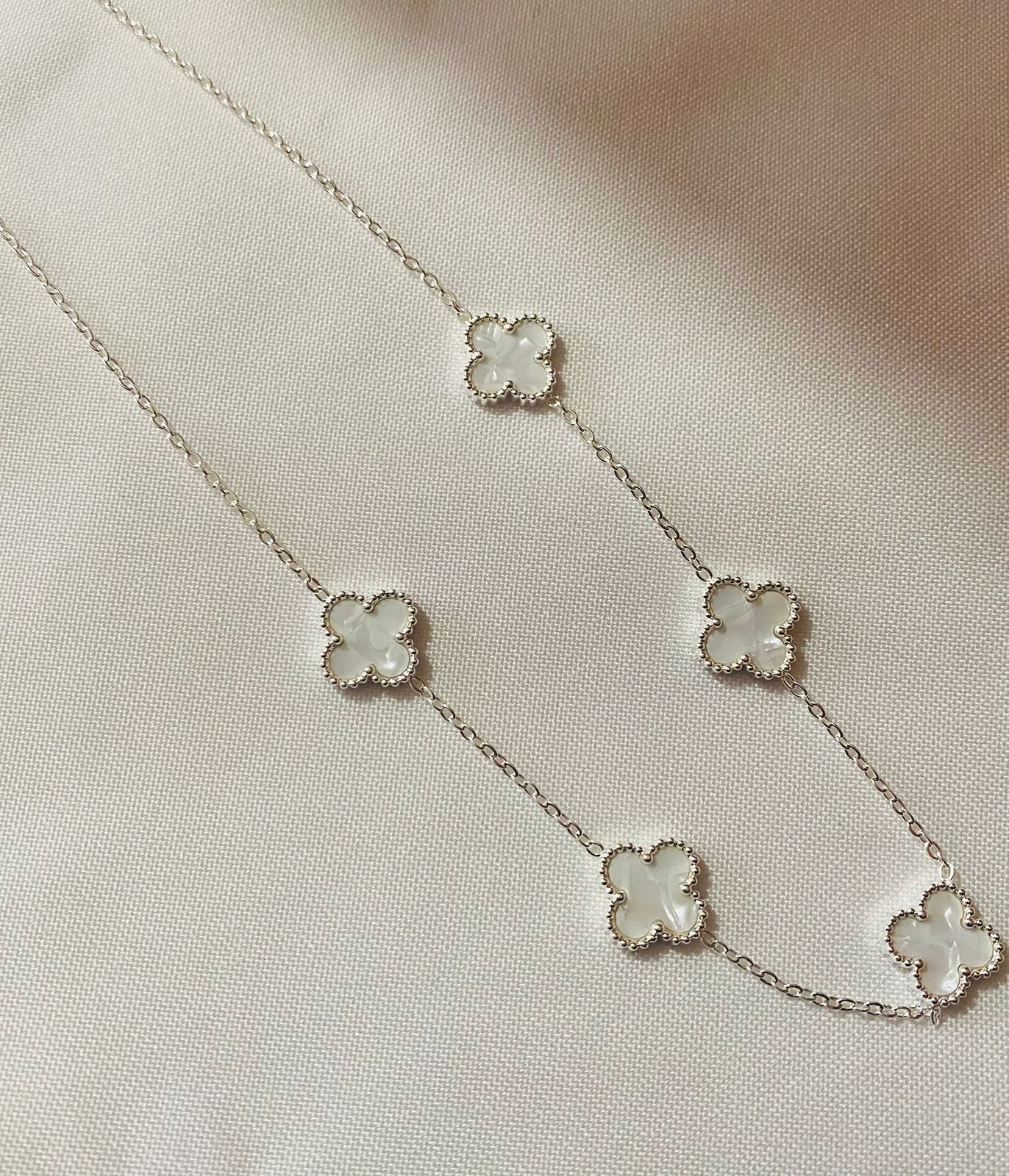Un primer plano de un collar con flores blancas sobre una tela blanca.