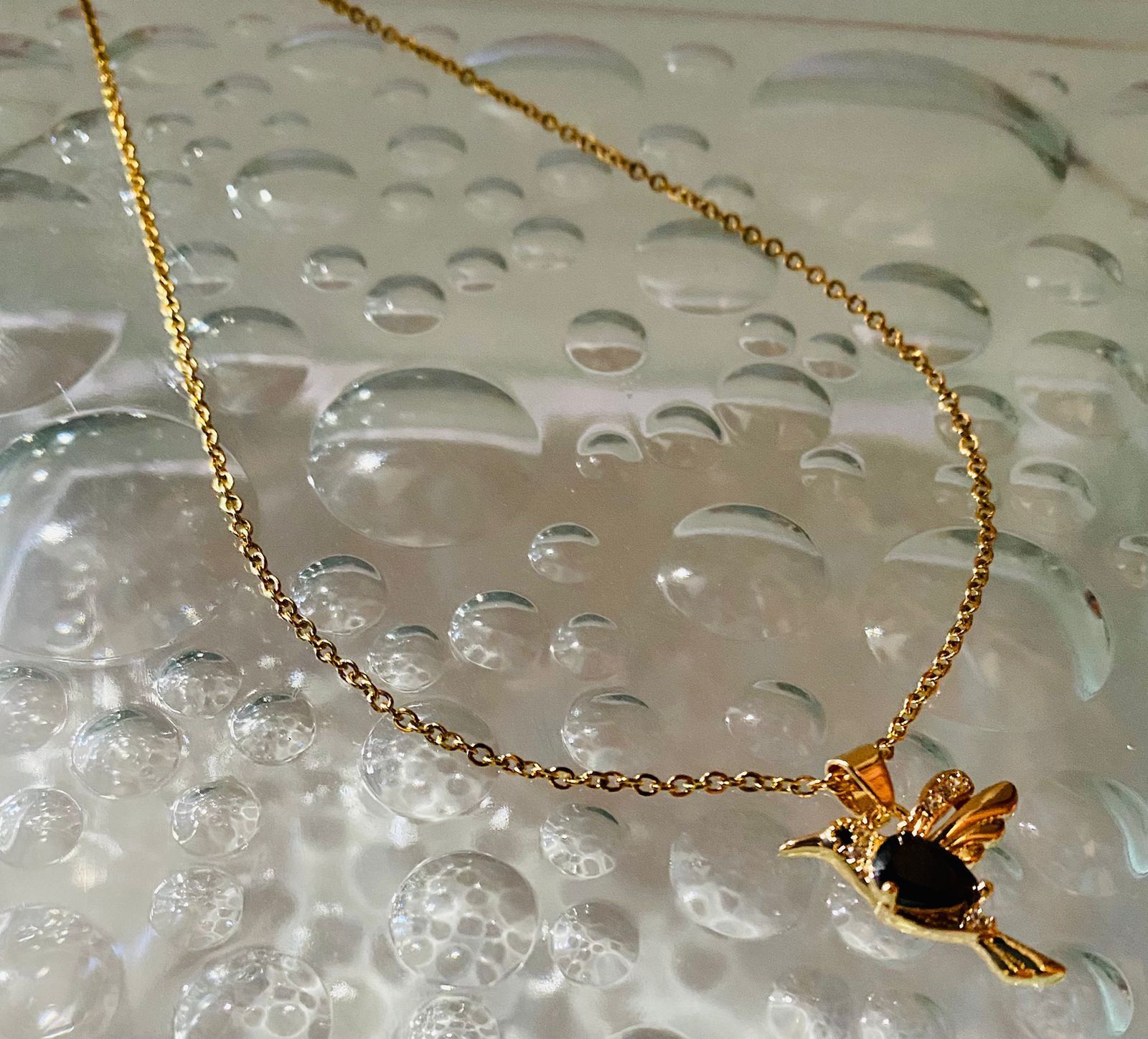 Un collar de oro con un colgante de pájaro en una cadena.