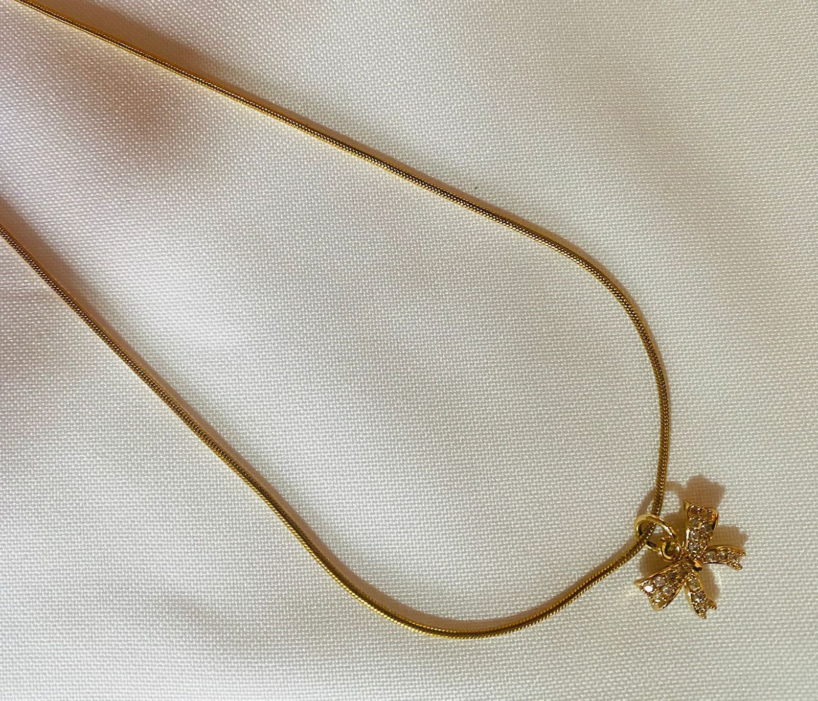 Un collar de oro con un colgante de copo de nieve sobre una tela blanca.