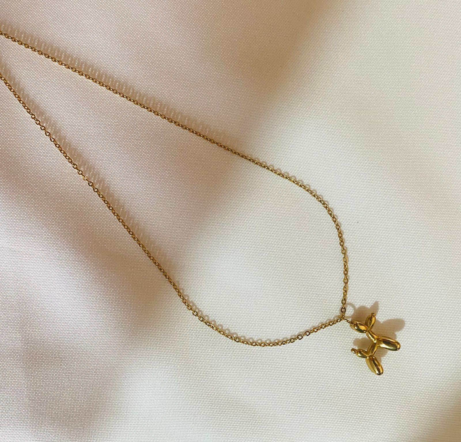Un primer plano de un collar de oro con un colgante sobre una tela blanca.