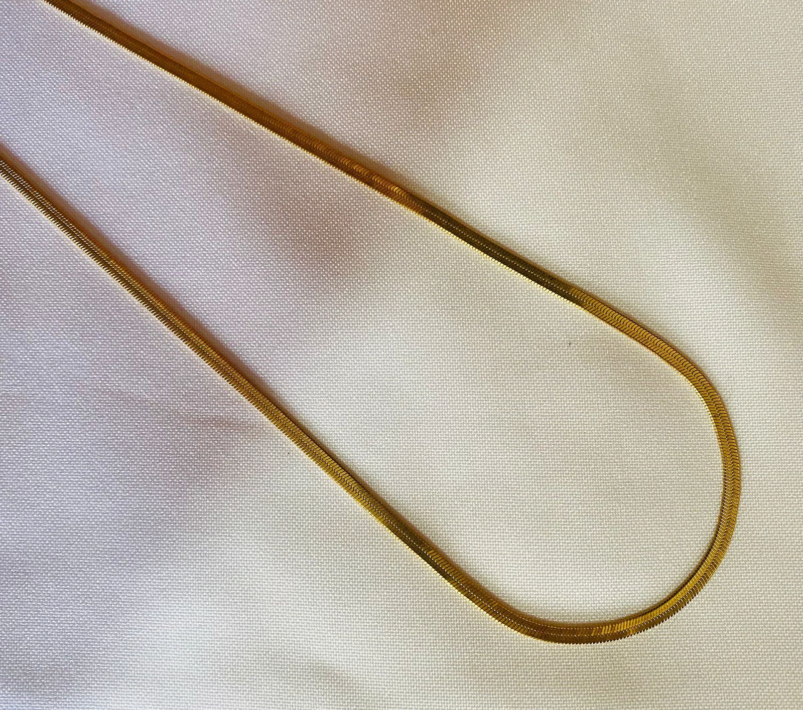 Un primer plano de una cadena de oro sobre una tela blanca.