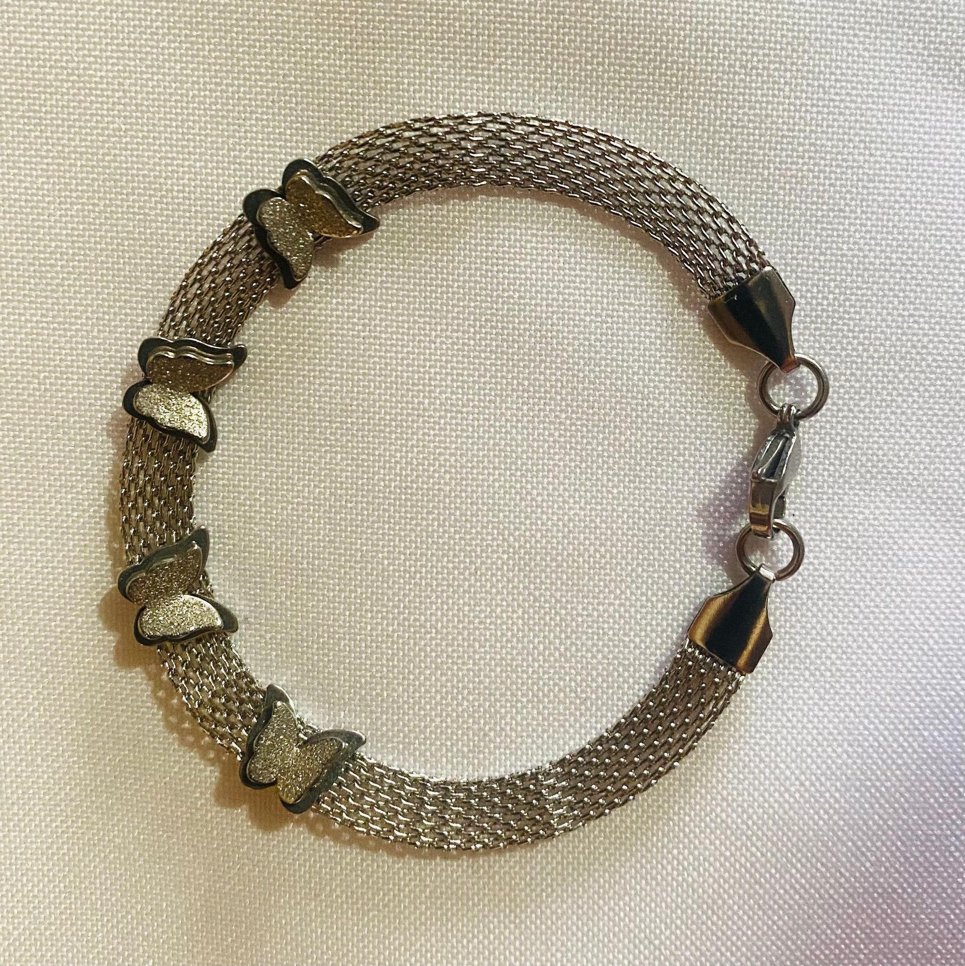 Una pulsera de plata con corazones reposa sobre un paño blanco.