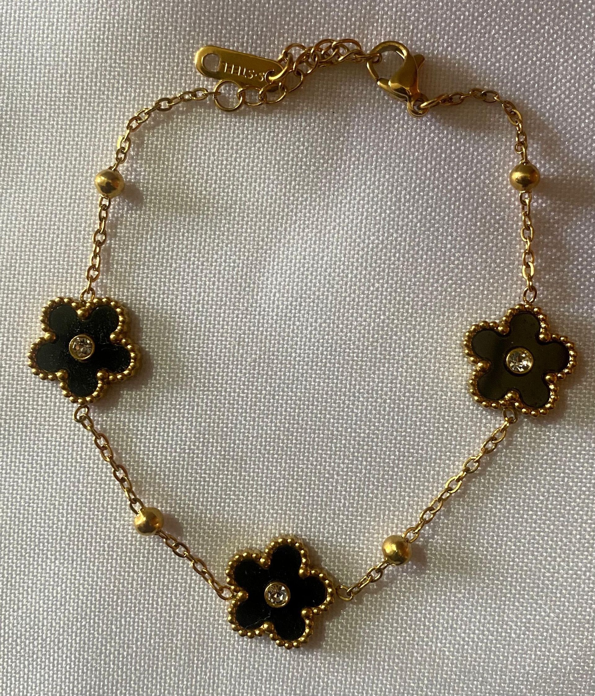 Una pulsera de oro con flores negras y diamantes.