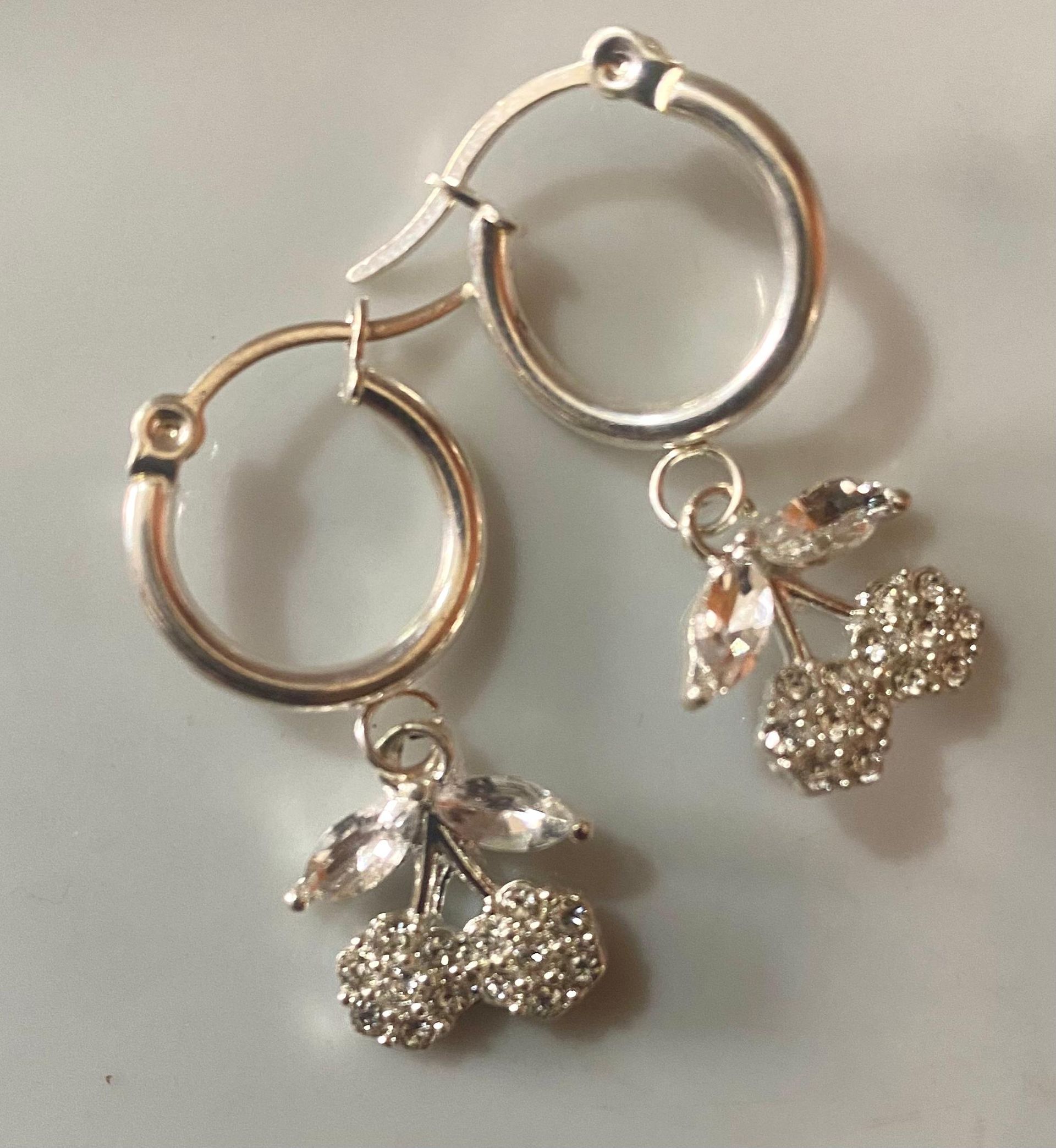 Un par de pendientes de aro de plata con cerezas.
