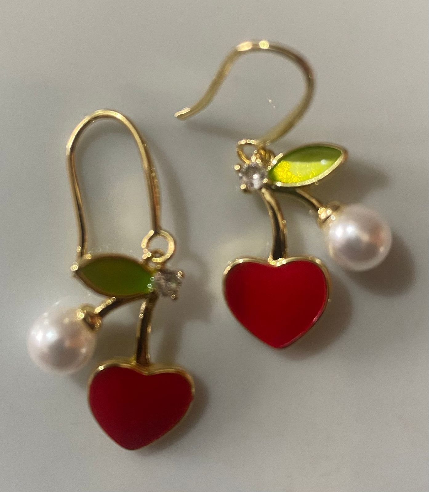 Un par de pendientes en forma de cereza con perlas.