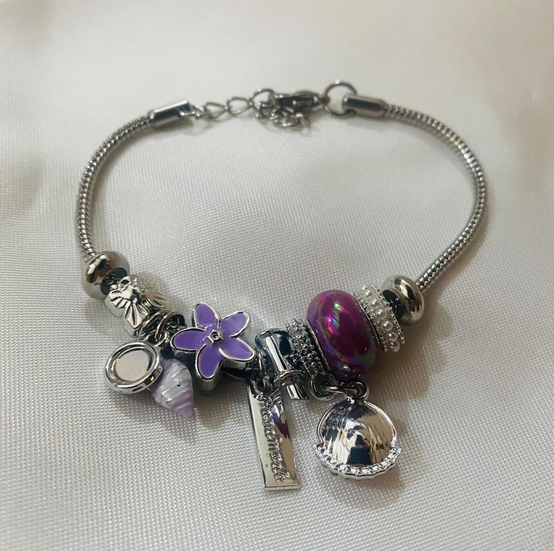 Una pulsera de plata con cuentas moradas y una flor morada.