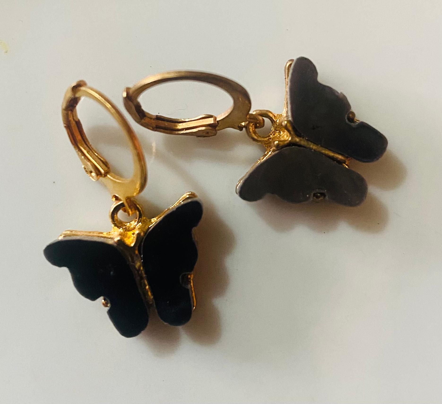 Un par de pendientes de mariposa negra sobre una superficie blanca.