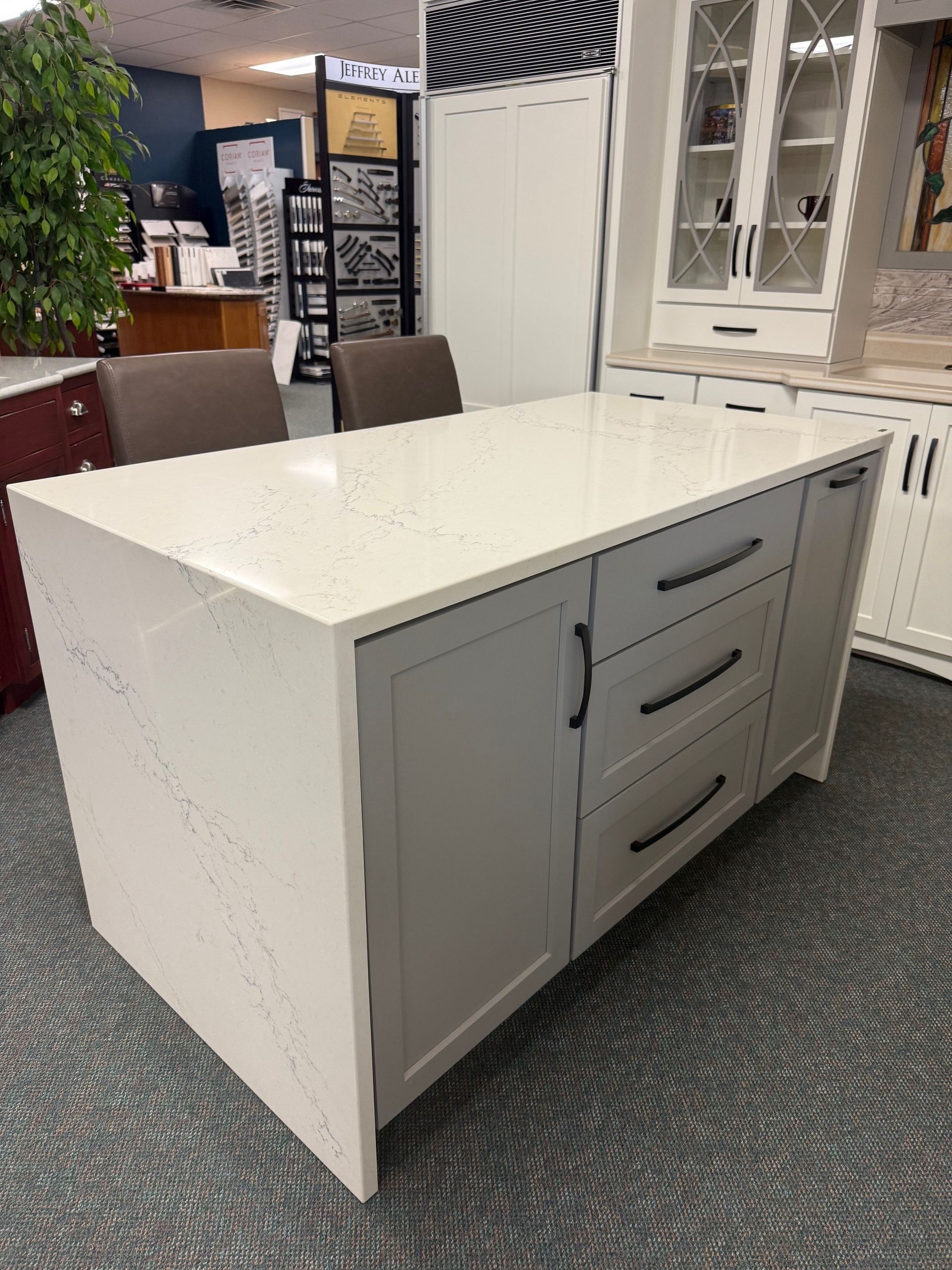 A large white island with drawers and cabinets in a kitchen showroom.
