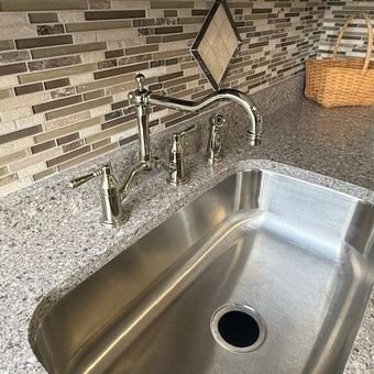 A stainless steel kitchen sink with a faucet and a basket on the counter. A stainless steel kitchen sink with a faucet and a basket on the counter.