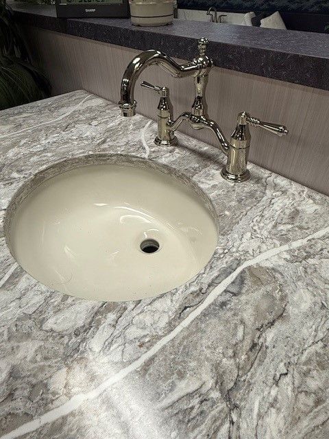 A bathroom sink with a faucet on a marble counter top.