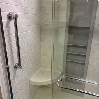 A bathroom with a walk in shower and a corner seat. A bathroom with a walk in shower and a corner seat.