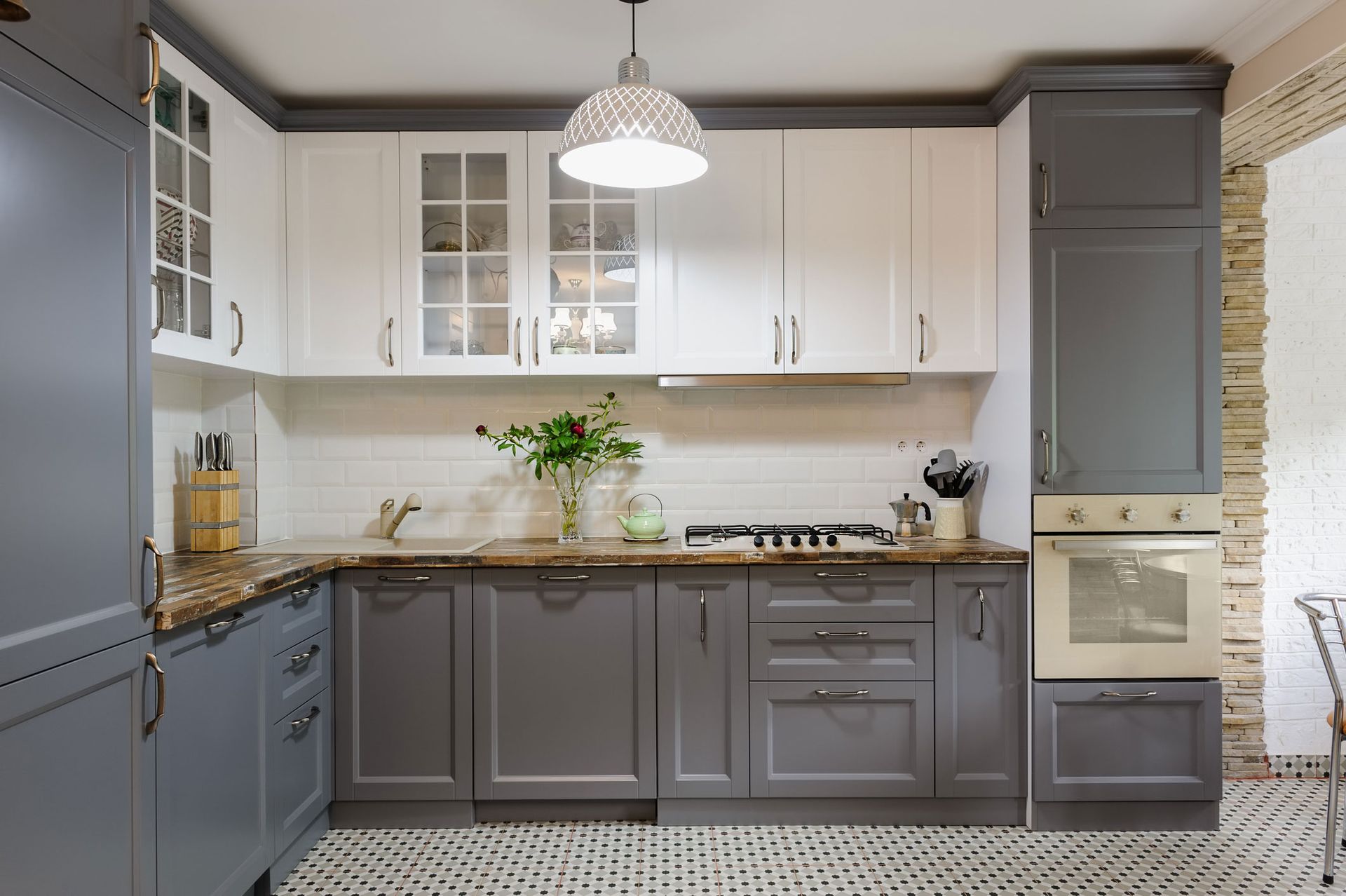 A kitchen with gray and white cabinets and a stove top oven.