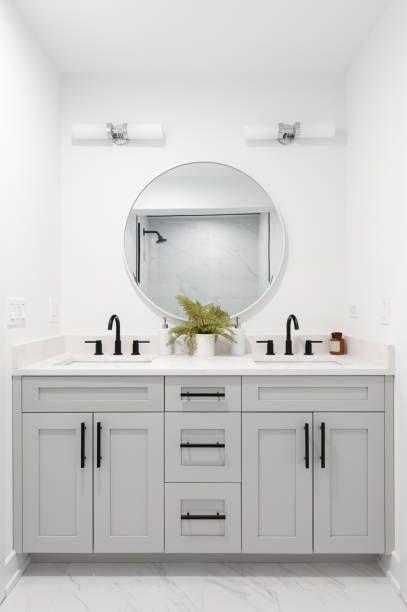 A bathroom with two sinks and a round mirror.