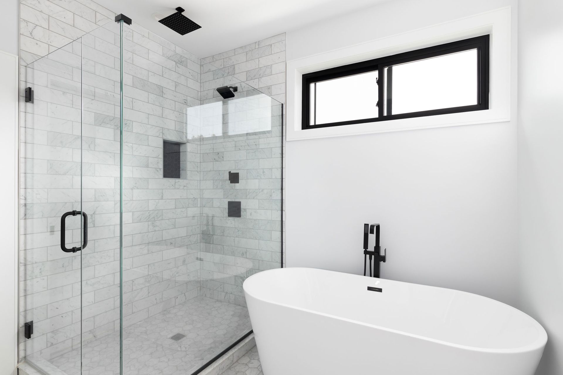 A bathroom with a white tub, shower and window