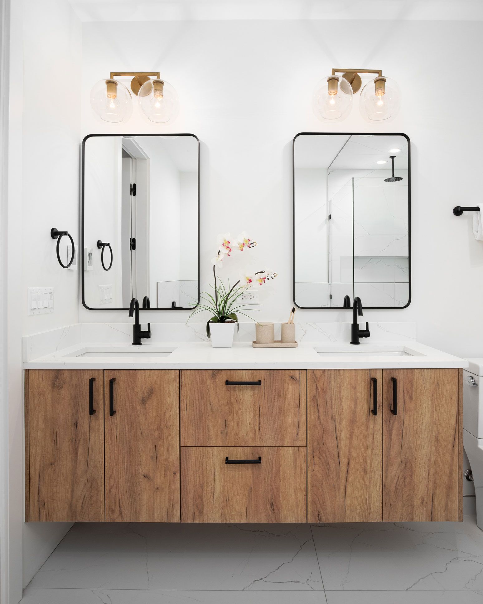 A bathroom with two sinks, two mirrors, and wooden cabinets.