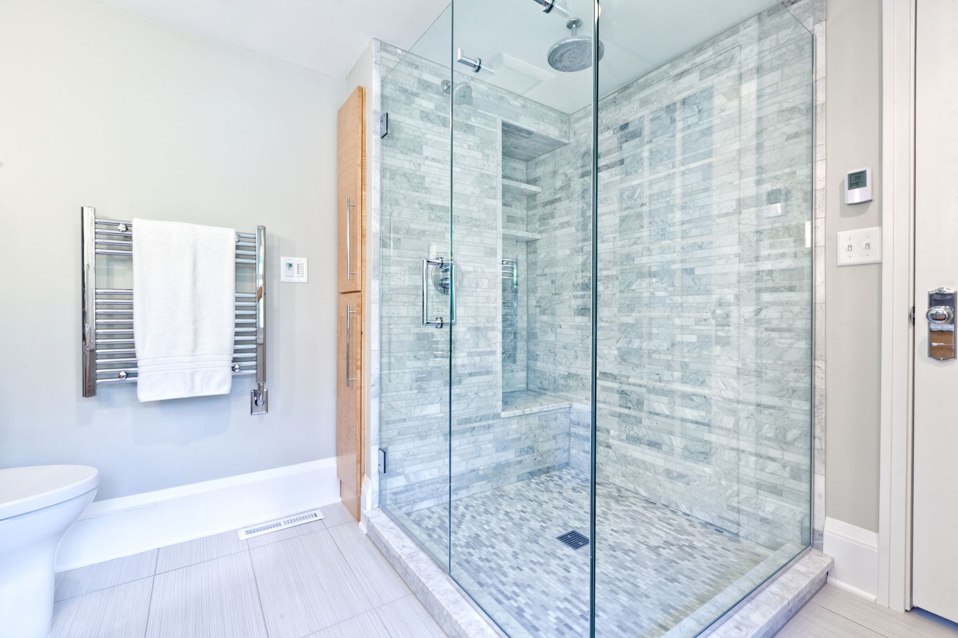 A bathroom with a walk in shower with a glass door.