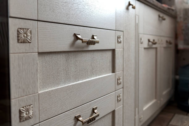 A kitchen with white cabinets and drawers with gold handles.