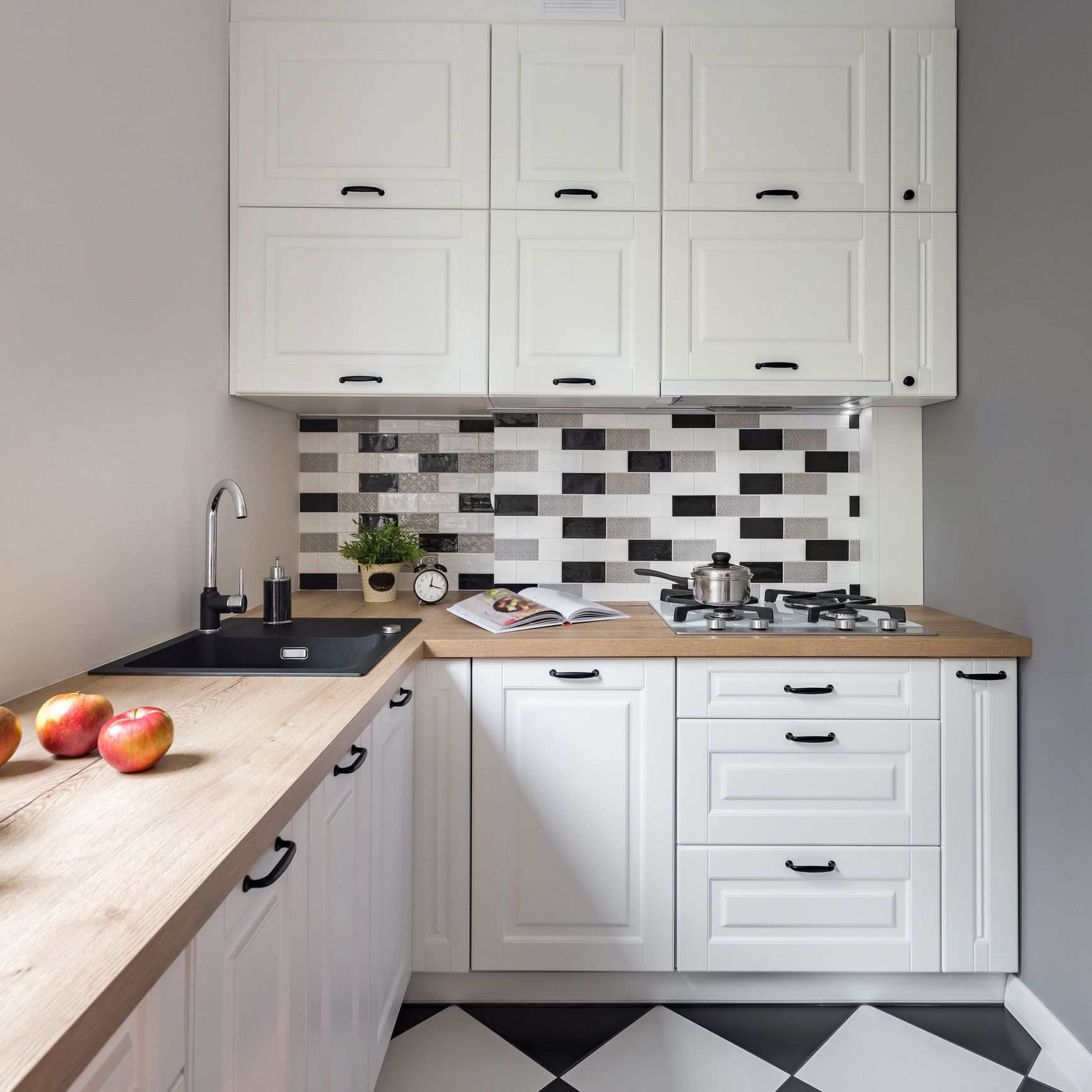 A kitchen with white cabinets and a black and white checkered floor