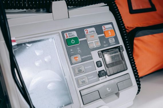 Portable defibrillator with instruction panel and screen, shown in a black carrying case