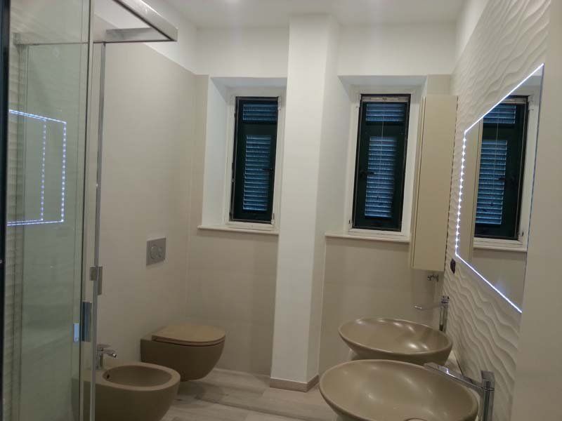 vista frontale di bagno moderno con box doccia in vetro, lavabi , specchio, bide e arredo da bagno