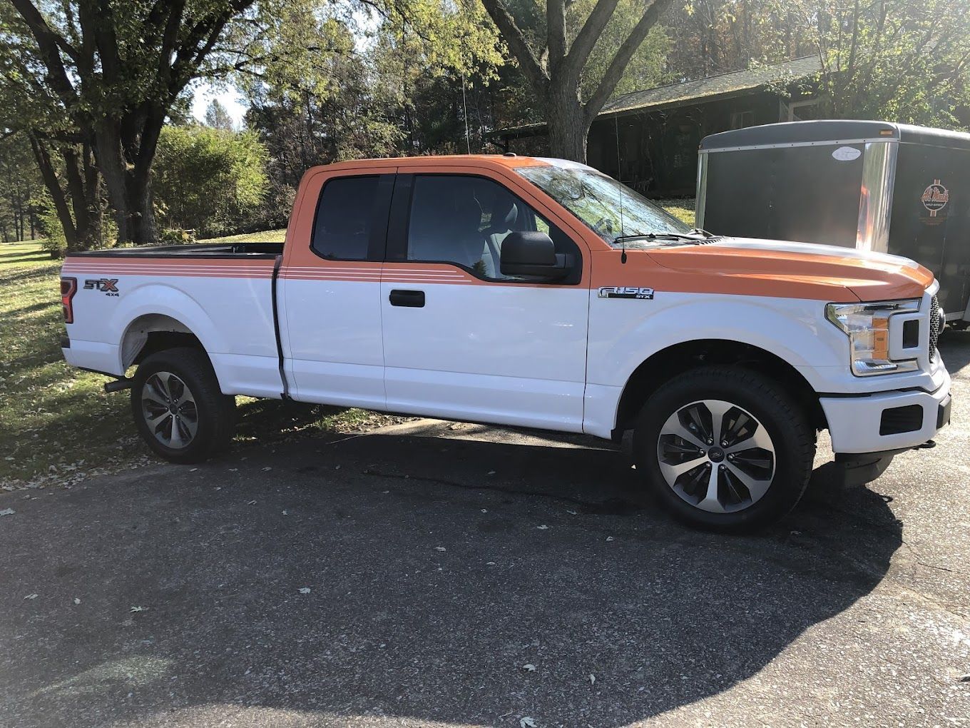 A white and orange pickup truck is parked in a parking lot.