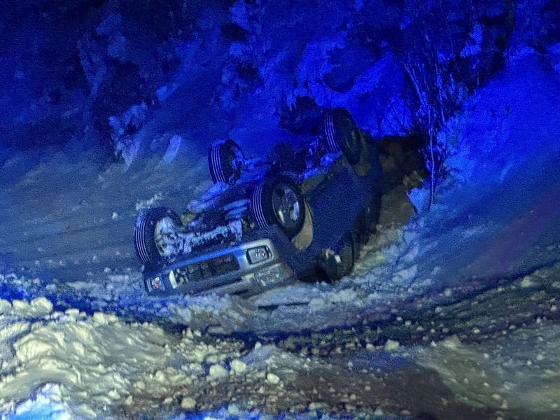 A car is on its side in the snow.